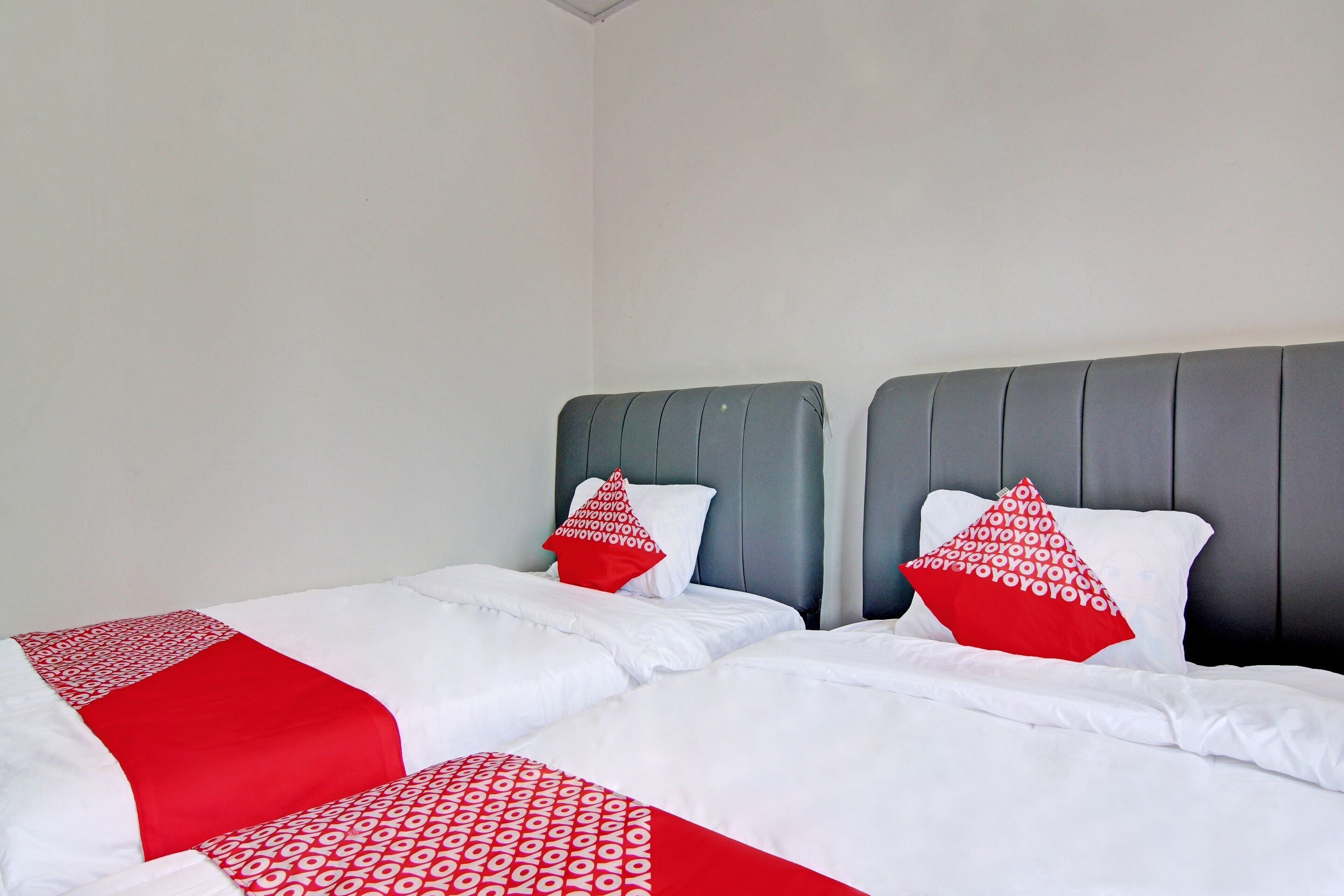 A hotel room with two beds, each with white bedding and red accents.