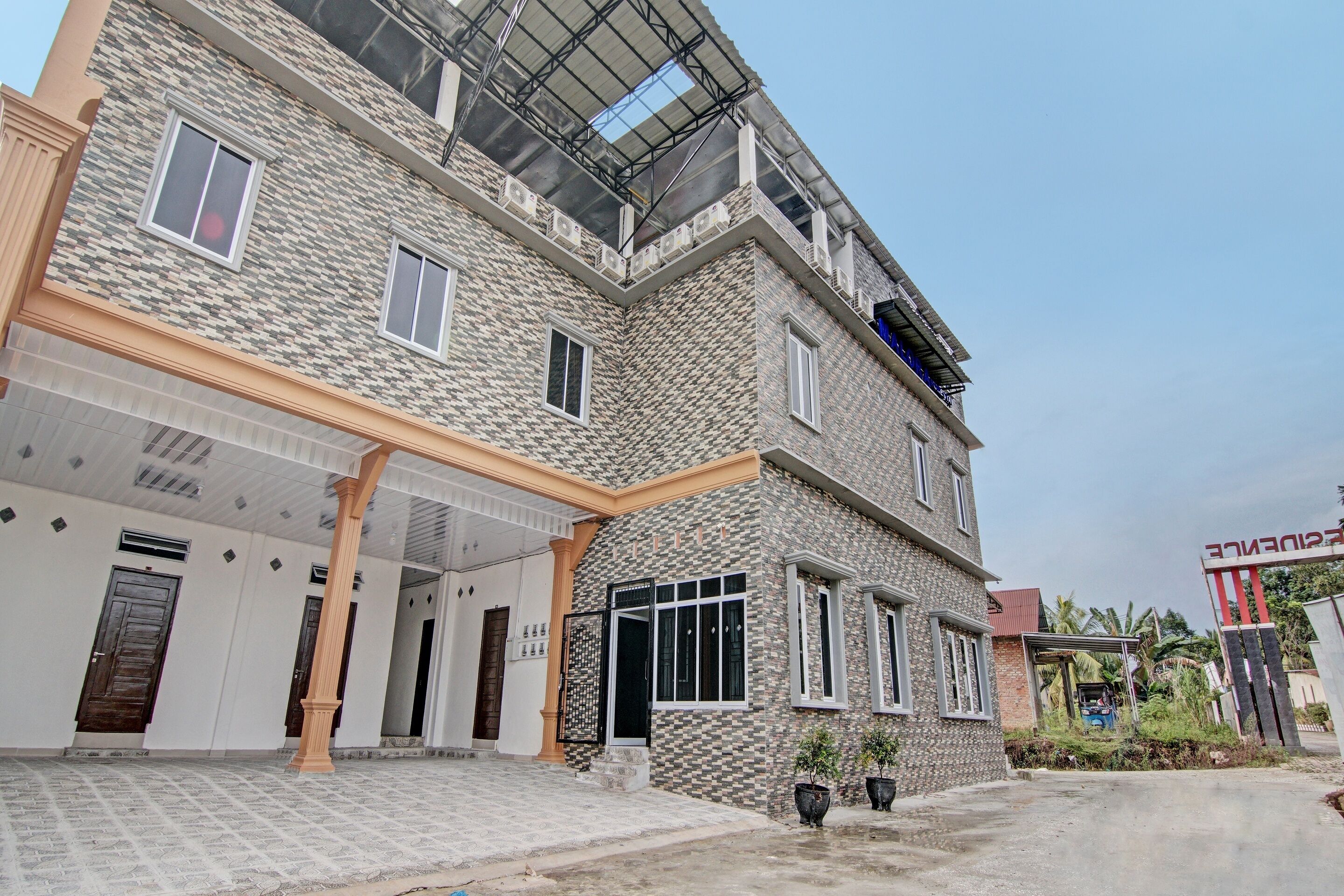 A multi-story building with a patterned facade, a covered entrance, and a gated driveway.