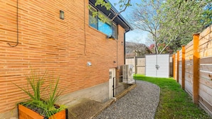 Una casa in mattoni con un vialetto sterrato che conduce a una recinzione in legno.