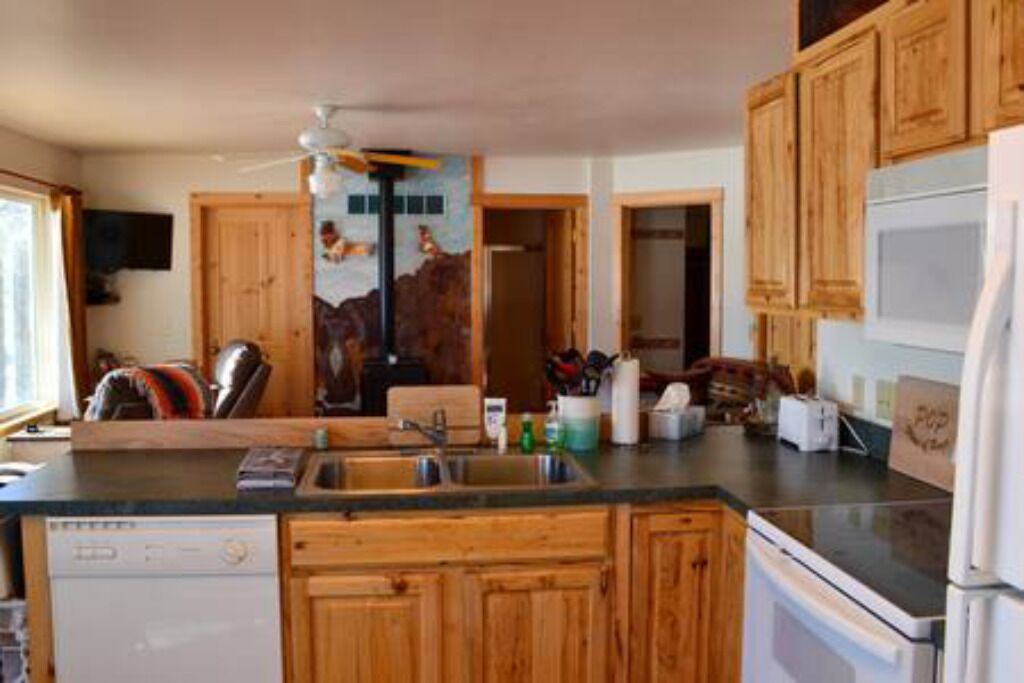 A kitchen with wooden cabinets, a dishwasher, a refrigerator, and a sink.