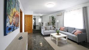 Un salon moderne avec un canapé gris, une table basse blanche et un tableau accroché au mur.