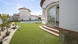 Un jardin bien entretenu, doté d’une pelouse artificielle, d’une piscine et d’un espace patio.