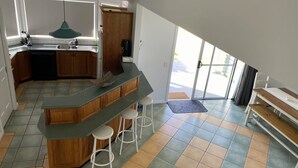 A modern kitchen with a curved island, wooden cabinets, and a large window.