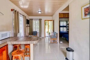 Un'ampia cucina con un tavolo in legno, due sgabelli, un forno a microonde e un cestino.