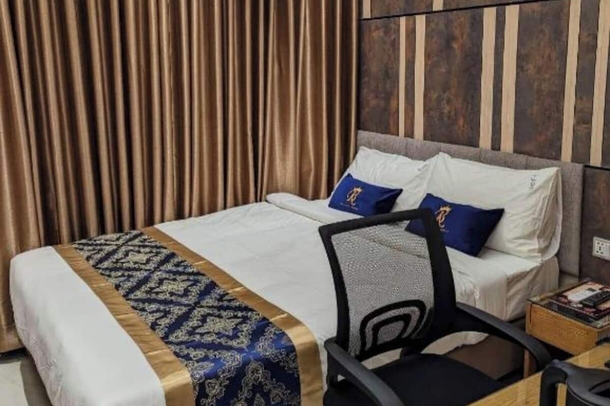 A hotel room with a large bed, a desk with a chair, and a coffee maker.