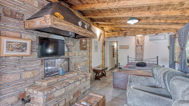 Una habitación rústica con chimenea de piedra, televisión y un sofá cómodo.