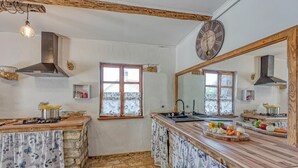 Una cocina con encimera de piedra, vigas de madera, estufa a gas, lavaplatos y un espejo grande.