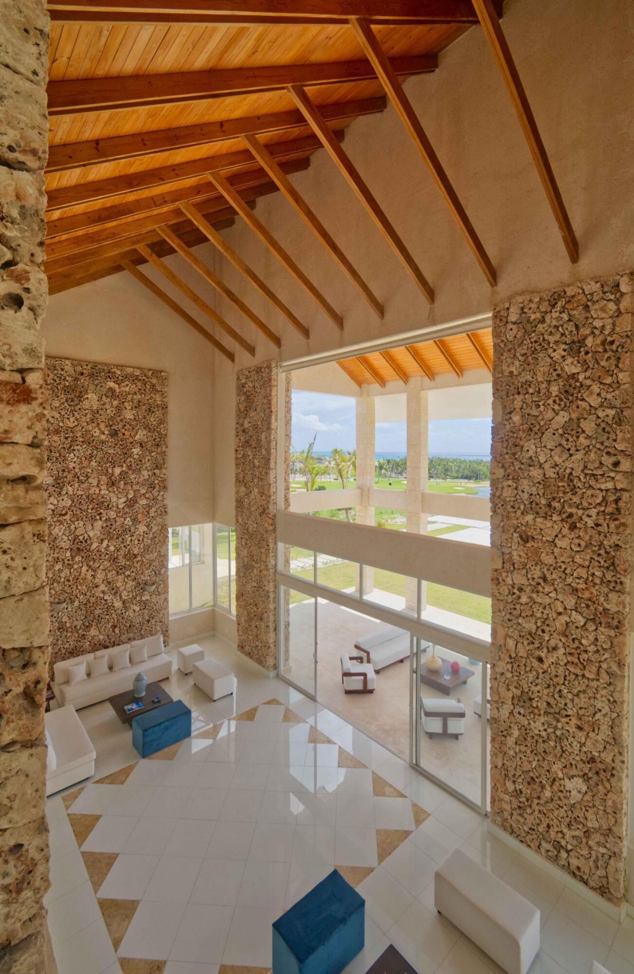 A spacious room with a high ceiling, large windows, and a view of a landscaped area.