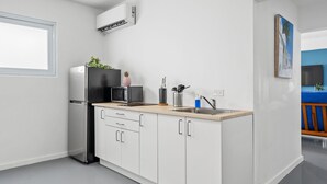 A modern kitchen with white cabinets, a black refrigerator, a microwave, and a sink.