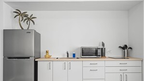 A modern kitchen with a stainless steel refrigerator, a microwave, and white cabinets. - Otium Rentals Best Condado Location Near Beach (San Juan)
