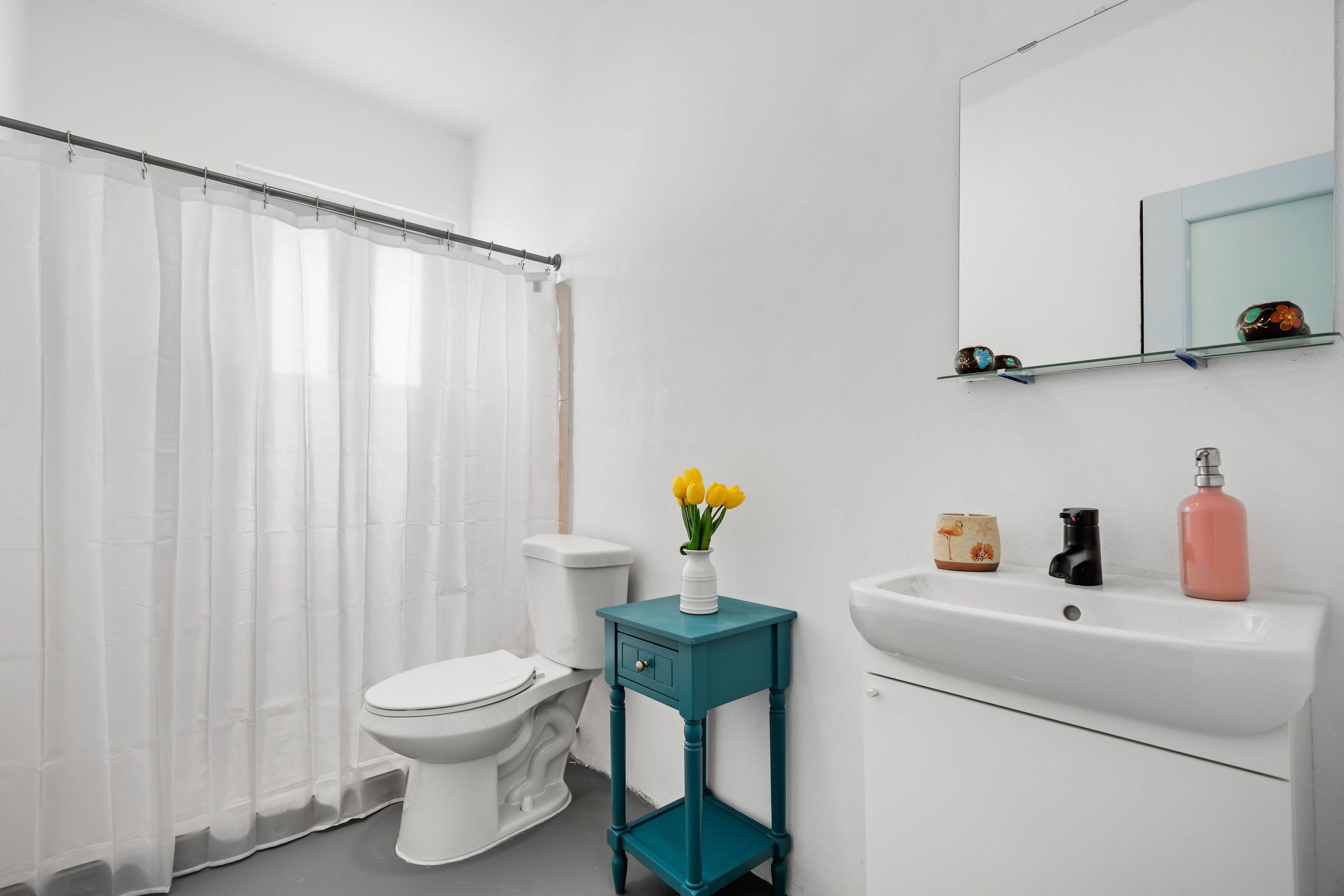 A bathroom with a toilet, a sink, a mirror, and a shower curtain.