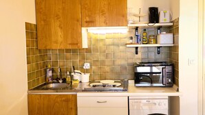A compact kitchen with wooden cabinets, a microwave, a toaster, and a dishwasher. - Sea View Apartment in Saint-Clair, 400 m from the beach! (Le Lavandou)