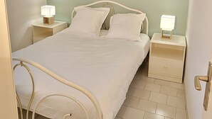 A bedroom with a bed, two bedside tables, a hanging light fixture, and a door. - Sea View Apartment in Saint-Clair, 400 m from the beach! (Le Lavandou)