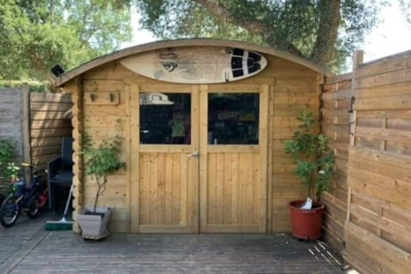 A wooden shed with two doors, a small window, and a roof.