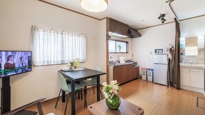 Ein modernes Wohnzimmer mit Fernseher, Essbereich und Küche.