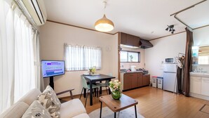 Ein Wohnzimmer mit Sofa, Couchtisch, Fernseher und einem Essbereich mit Tisch und Stühlen.