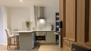 A modern kitchen with a central island, bar stools, a built-in oven, and a stainless steel range hood.