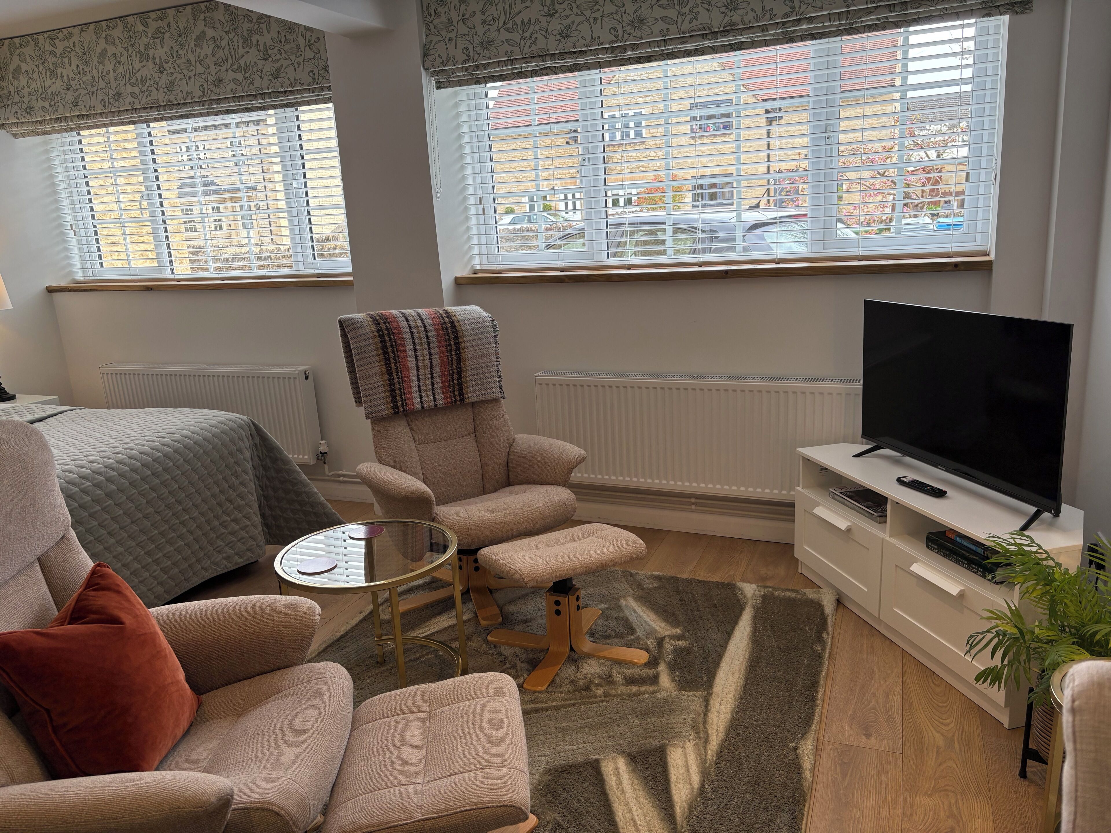 A modern living room with a sofa, armchair, TV, and a small table.