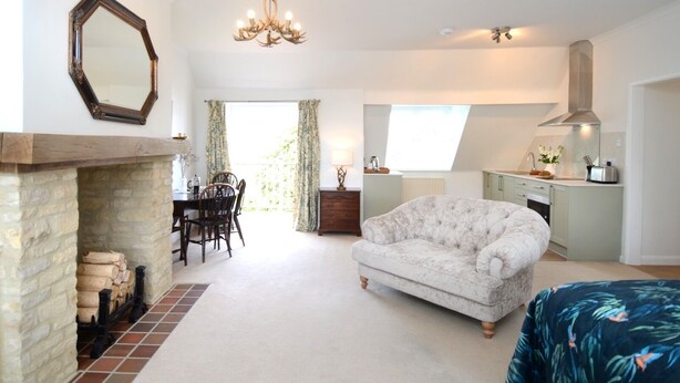 A spacious living room with a fireplace, a dining area, and a kitchen.