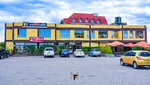 A multi-story building with a yellow facade, a red roof, and multiple storefronts including one for Eaglesvale Resort. - Eaglesvale Resort Naivasha (Naivasha)
