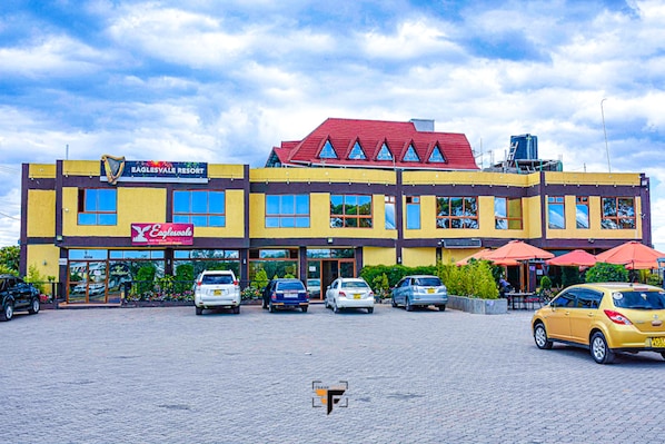 A multi-story building with a yellow facade, a red roof, and multiple storefronts including one for Eaglesvale Resort.
