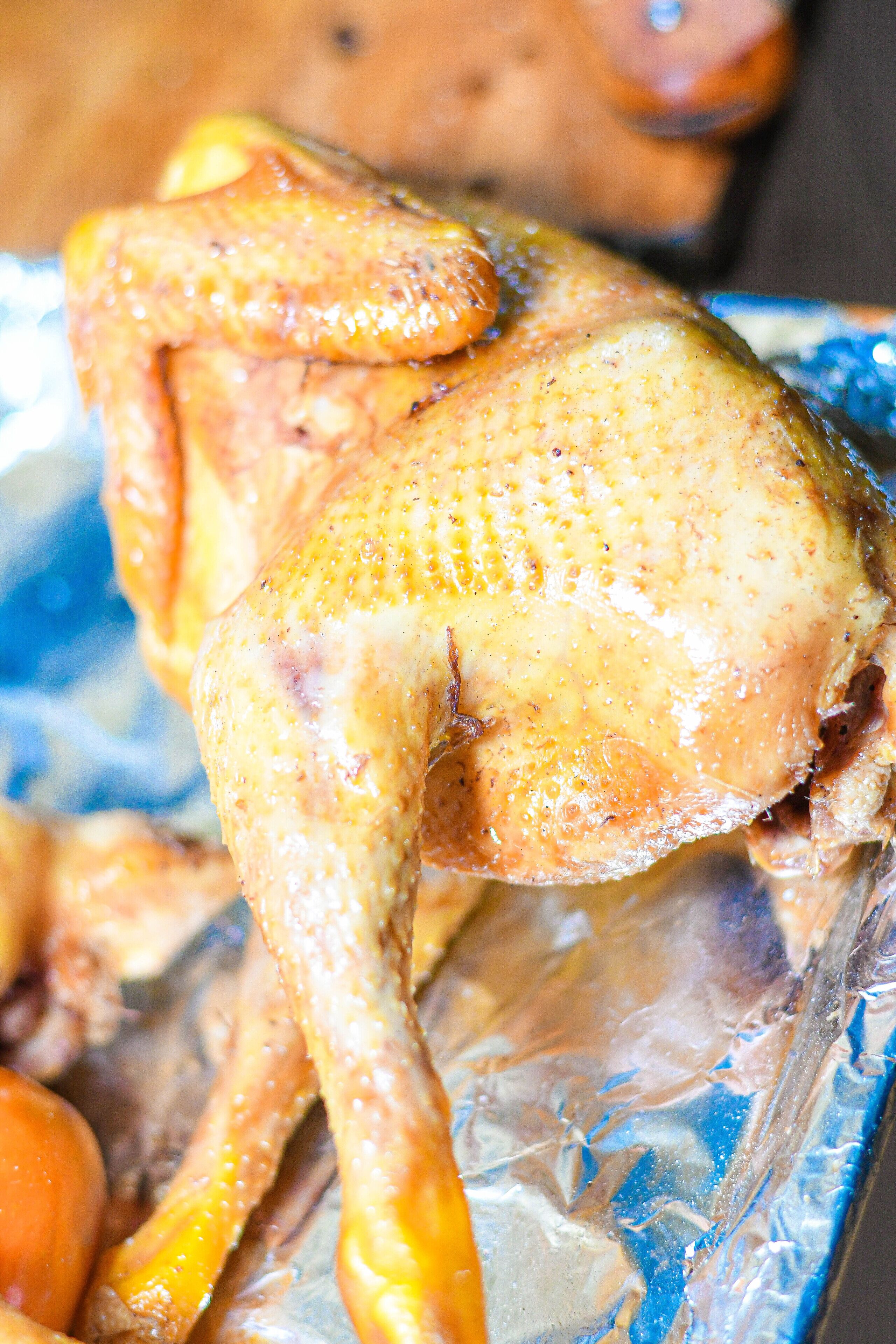 A roasted chicken on a foil tray.