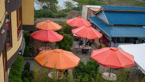 A patio area with multiple tables and chairs, surrounded by red umbrellas, overlooking a body of water. - Eaglesvale Resort Naivasha (Naivasha)