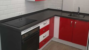 A kitchen with white and red cabinets, a black countertop, and a built-in oven.