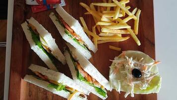 Ein halbiertes Sandwich, Pommes Frites und ein gemischter Salat mit einer Olive auf einer Holzbrett.