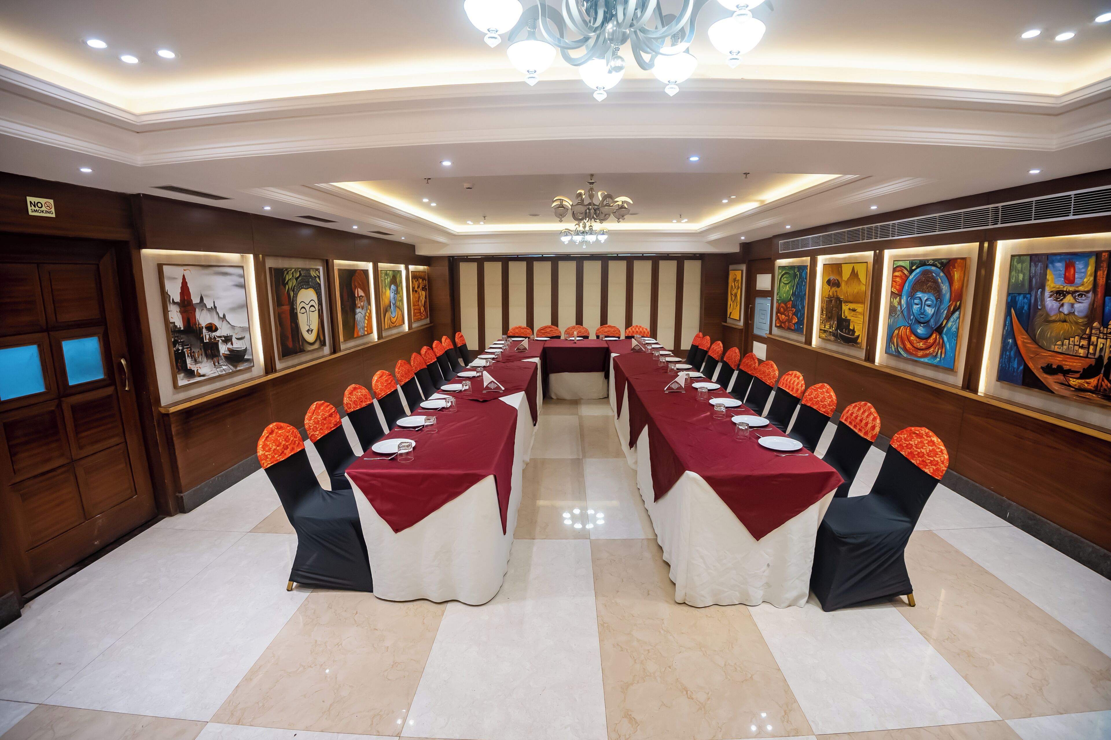 Un salón de conferencias con una larga mesa, sillas y obras de arte en las paredes.