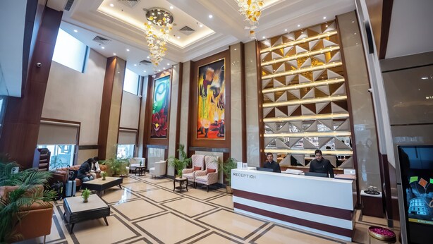 Un moderno vestíbulo de hotel con mostrador de recepción, zona de estar y detalles decorativos como candelabros y obras de arte.