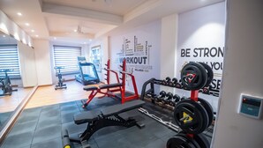 Un gimnasio con equipamiento de ejercicio, una pared con citas motivacionales y un espejo.