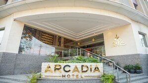 Exterior del Hotel Arcadia, con entrada de piedra, escalones y plantas en macetas.
