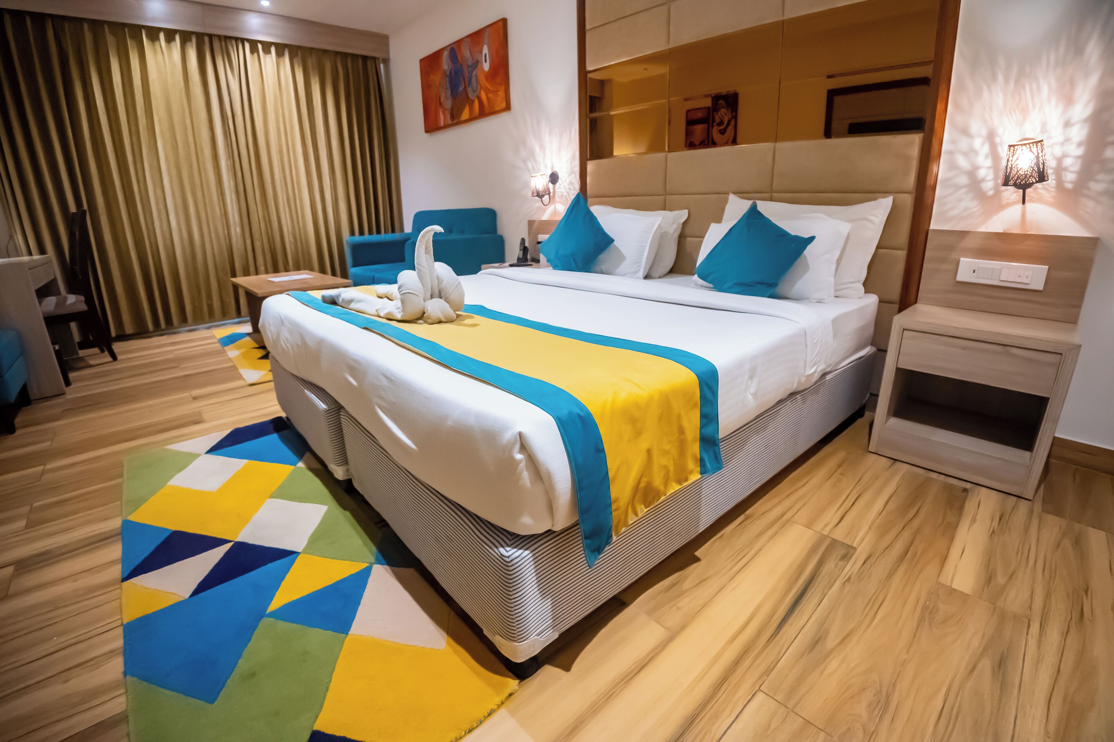 Una habitación de hotel con una cama grande, un escritorio, una silla, un sofá y un televisor instalado en la pared.