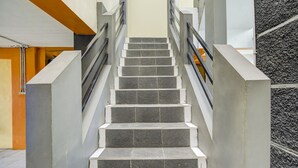 Eine Treppe mit schwarz-weißen Stufen, Metallgeländern und einer Betonwand an einer Seite.
