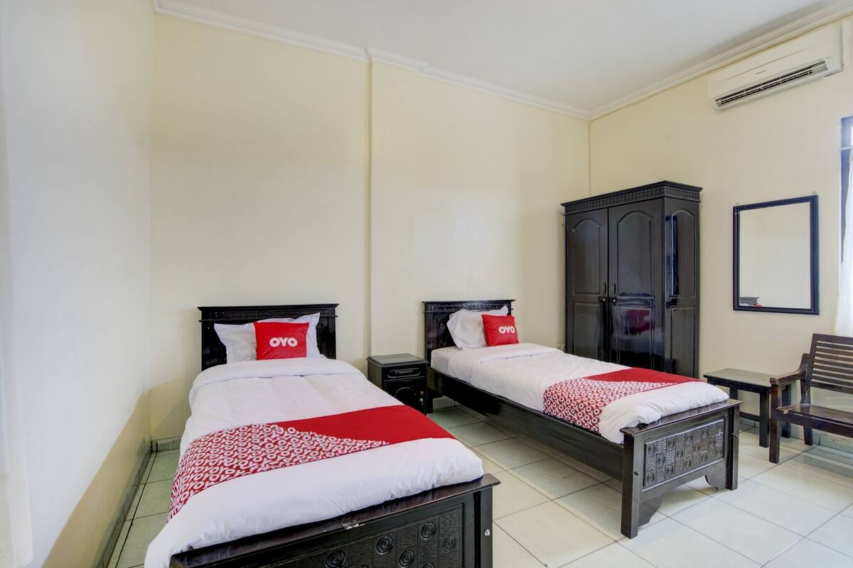 Een hotelkamer met twee bedden, een garderobe, een stoel en een spiegel.
