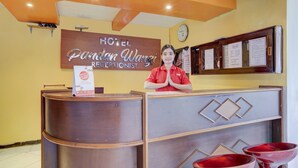 Ein Empfangstresen mit einem Schild, das 'Hotel Paraman Wangri Rezeption' zeigt, einer Uhr und einer Speisekarte.