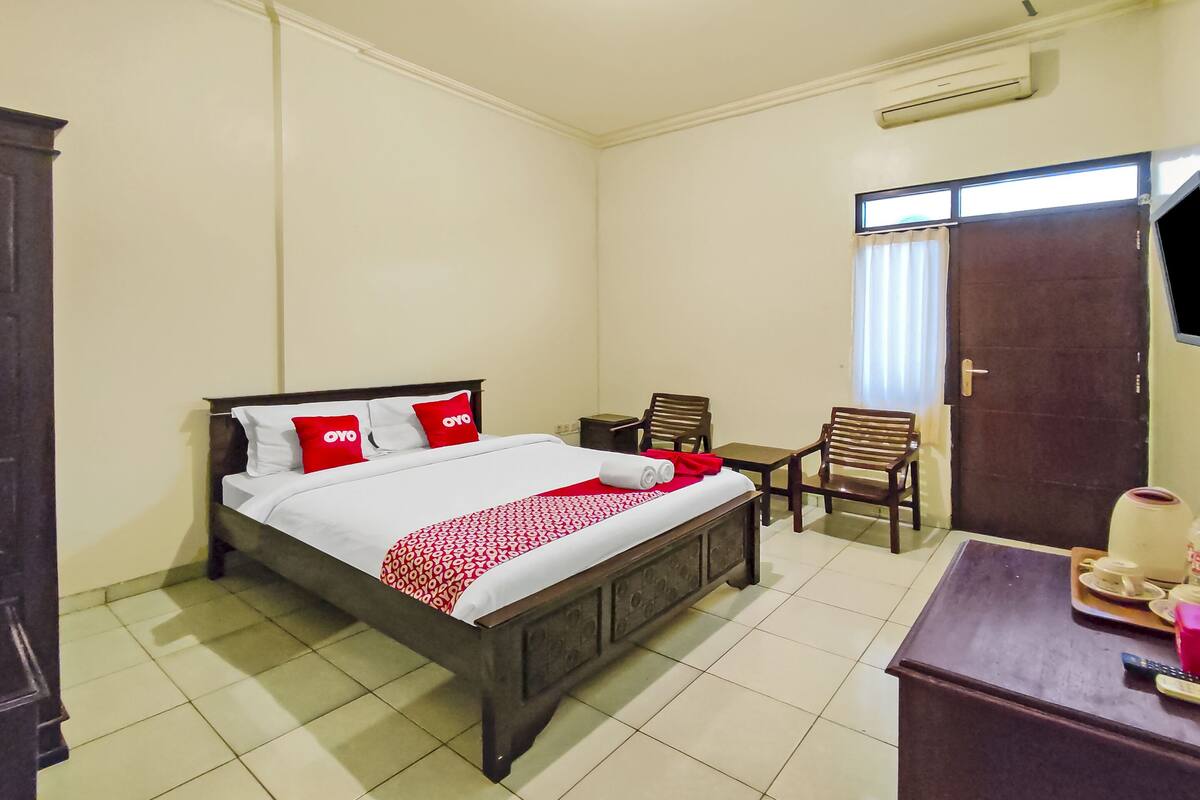 Een hotelkamer met een bed, bureau, stoel en een kledingkast.