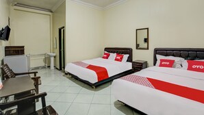 Ein Hotelzimmer mit zwei Betten, einem Schreibtisch und einem Sessel.