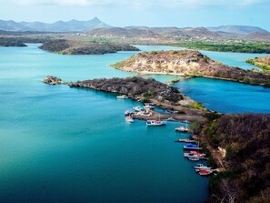 Une zone côtière où des bateaux sont amarrés à un quai, entourée d’eau et de collines.