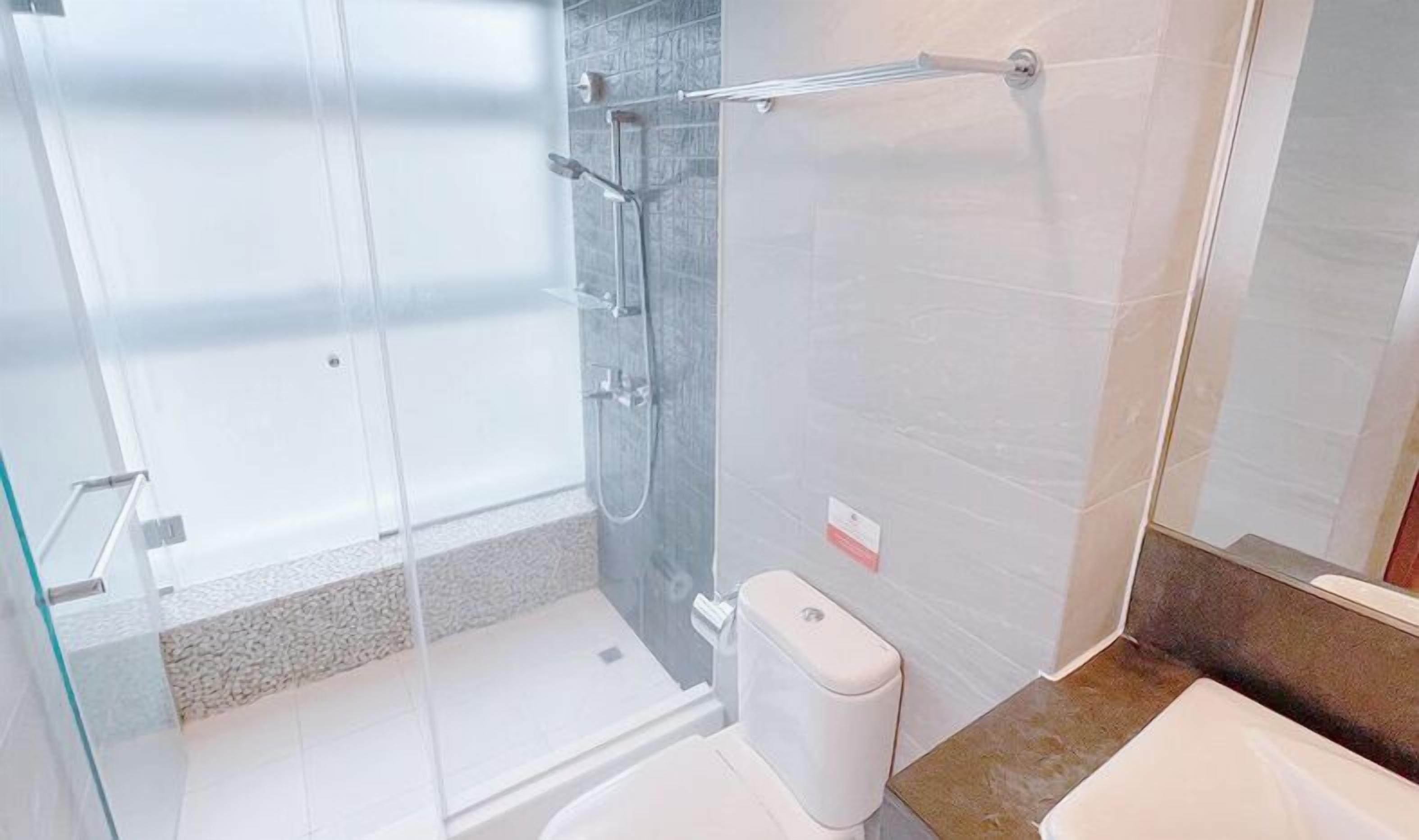 Un baño moderno con cabina de ducha de vidrio, inodoro y bañera.