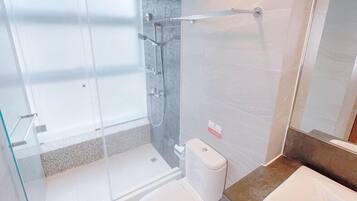 Un baño moderno con cabina de ducha de vidrio, inodoro y bañera.