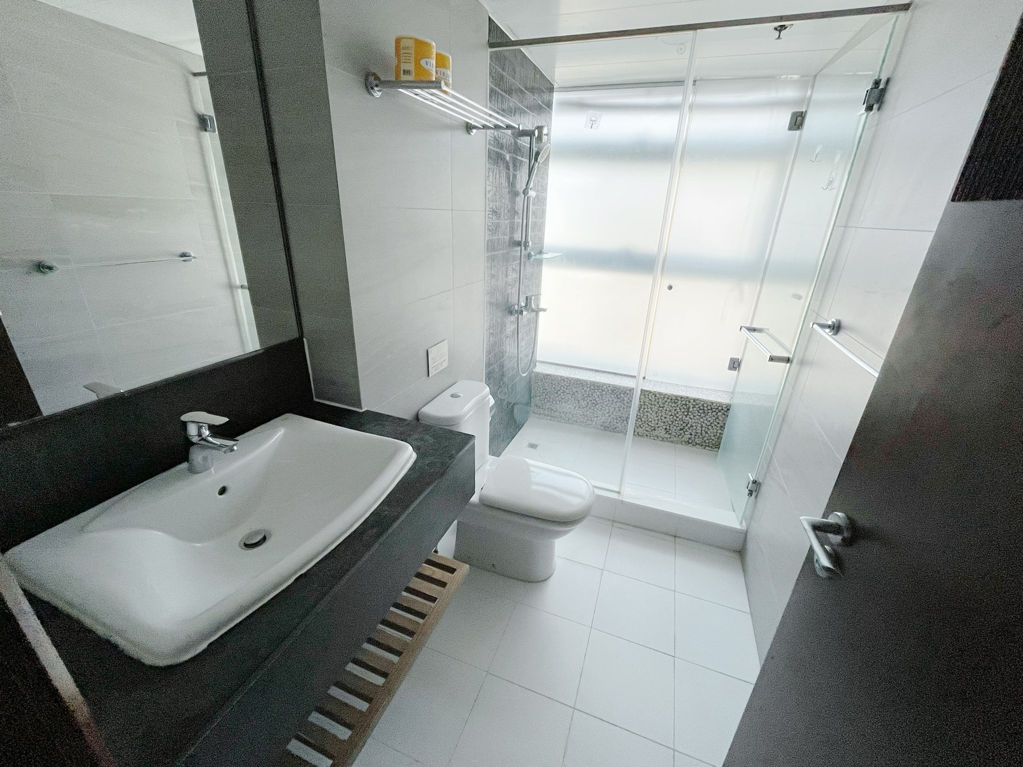 A modern bathroom with a large sink, toilet, and glass-enclosed shower.