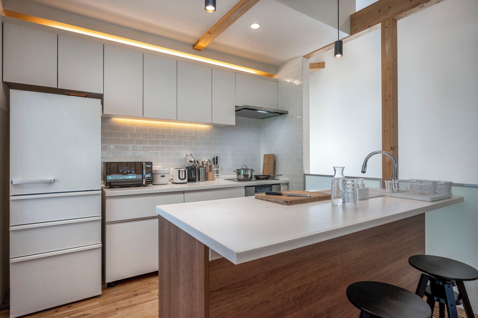 A modern kitchen with white cabinetry, a central island, and a wooden accent wall.