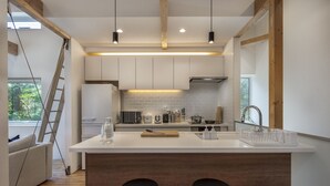 A modern kitchen with a central island, wooden beams, white cabinetry, and pendant lighting. - Homerunner by H2 Life (Kutchan)
