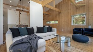 A modern living room with a sofa, ottoman, and glass coffee table. - Homerunner by H2 Life (Kutchan)