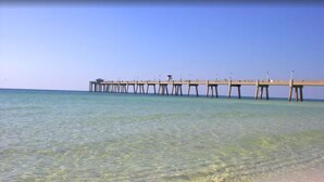 Une jetée s’avançant dans une eau claire, avec une plage de sable à son extrémité.