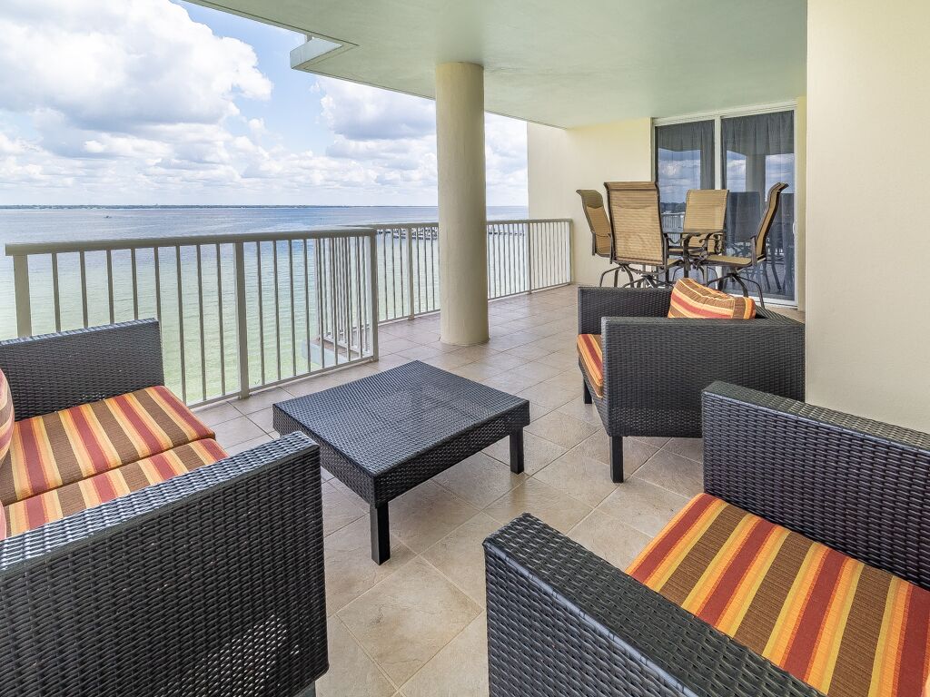 Een balkon met rieten meubilair en uitzicht op de oceaan.