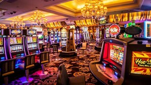 A casino floor with multiple slot machines and a large chandelier. - Luxury 3 Bed Palm Beach Strip Condo! (Noord)