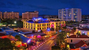 A hotel with multiple floors, outdoor seating areas, and a well-lit facade. - Luxury 3 Bed Palm Beach Strip Condo! (Noord)